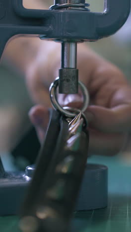cu: skilled woman tailor sets metal accessories on black leather choker with special press machine close view