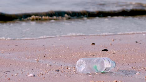 plastic bottle on sandy beach with waves