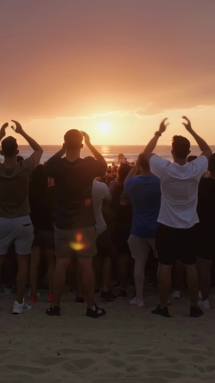 Video verticale: Reazione al sole che si avvicina all'orizzonte, folla in pantaloncini che alza braccia e telefoni in spiaggia.