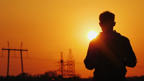 Tourist-With-A-Backpack-Goes-Forward-To-The-Big-Setting-Sun-And-The-City-Ahead-Against-A-Beautiful-O