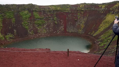 male photographer setting up camera at the kerid volcano in iceland with gimbal video walking forward