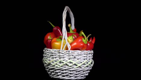 vegetarian healthy food, composition of vegetables,  rotation of a basket with peppers on a black background