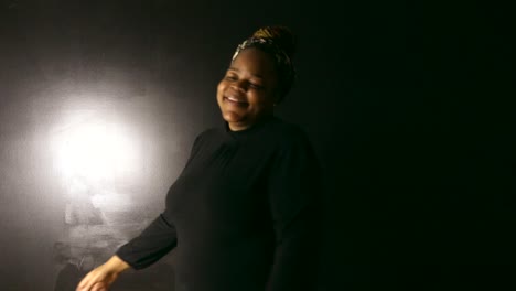 Happy-Black-woman-with-braids-spins-happily-while-smiling-and-looking-directly-in-camera