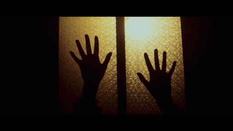 hands reaching through a window at night