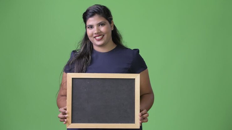 Young overweight beautiful Indian businesswoman against green background