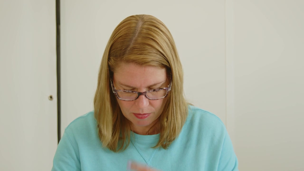 Donna in ufficio che legge un testo e si lecca il dito.