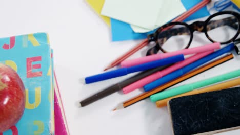 apple on stack of books with various stationery