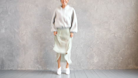 woman dancing in a grey hoodie and pleated skirt