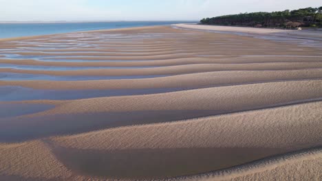 coastal sandy dunes with water rising over it, aerial drone view