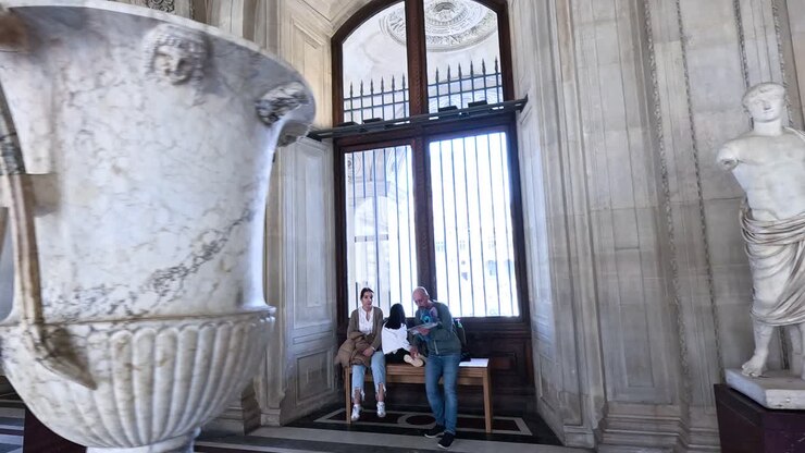 People exploring statues in the Louvre Museum