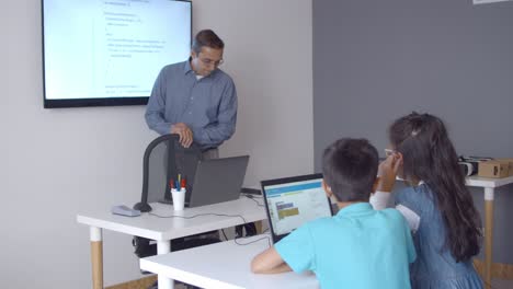profesor de ciencias de la computación de pie en su escritorio en clase