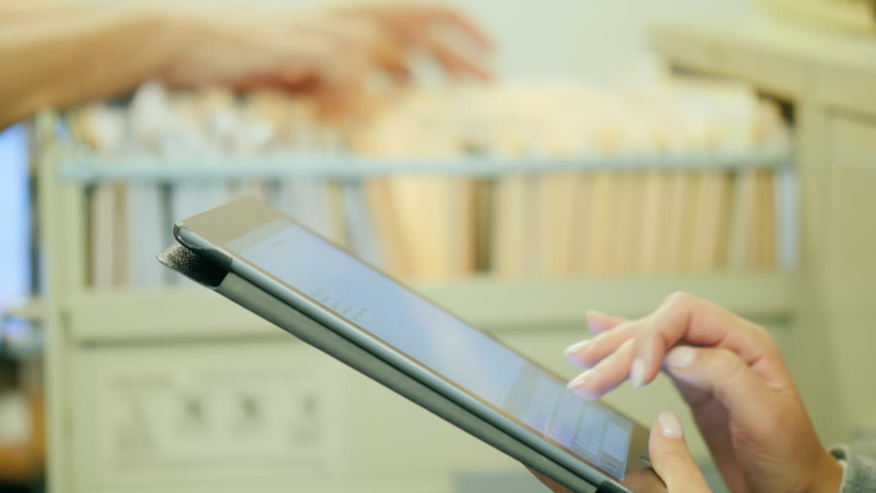 manos clasificando archivos en papel y manos usando tableta