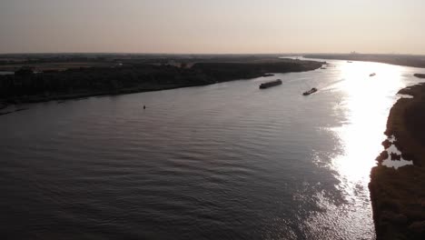 Luftsilhouettenansicht-Zweier-Schiffe,-Die-Abends-Entlang-Der-Sonnenbeschienenen-Oude-Mass-In-Barendrecht-Fahren