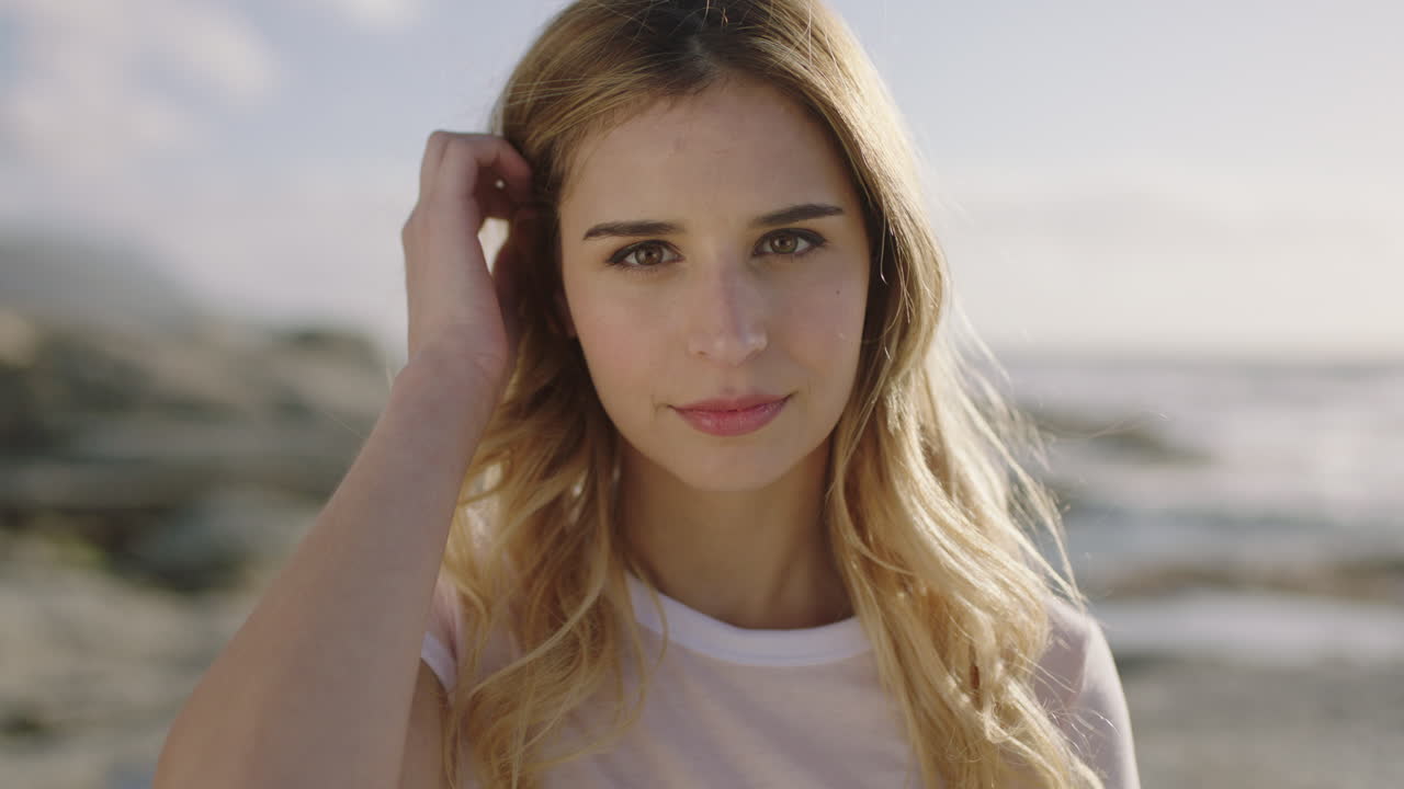 해변 에서 매력적 인 독립적 인 여자 를 포즈 하는 아름다운 금발 여자 의 포트레이트 를 가 ⁇ 게