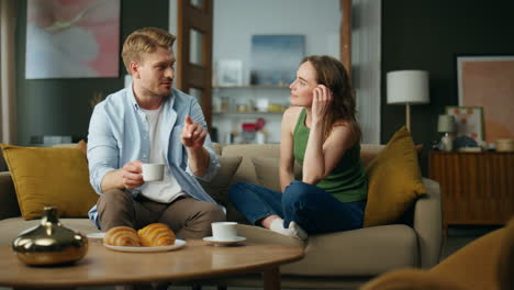cónyuges refrescantes bebiendo té en el interior del sofá. pareja disfrutando de café hablando
