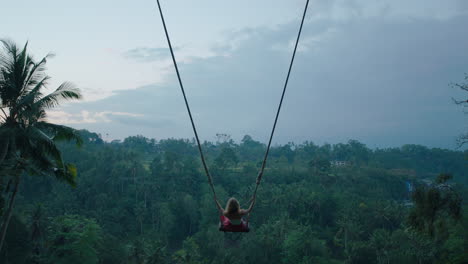 happy woman swinging over tropical jungle at sunrise travel girl enjoying exotic vacation sitting on swing in having fun holiday lifestyle freedom 4k