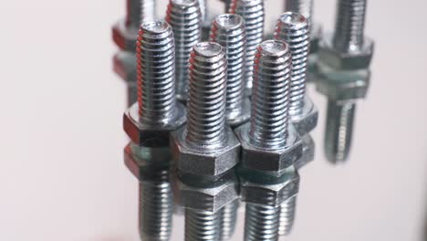 rotating group of galvanized metallic screws close-up. stainless steel bolts isolated on mirror reflective background.
