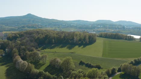 drone - aerial panorama fly over shot of a meadow with grass and bushes and the siebengebirge - seven mountains in the background 25p