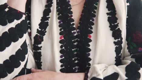 close-up of elderly female hands in authentic embroidered ukrainian attire with a red gemstone ring on the finger