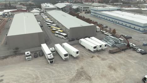 an industrial zone, with lost of truck and busses parked next to some industrial buildings, halls