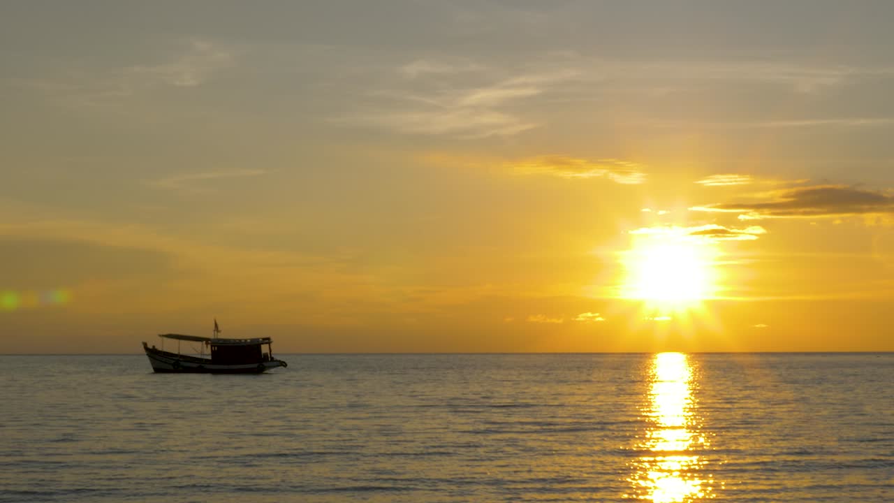 백그라운드에서 태양 설정과 함께 수평선에 낚시 보트의 실루엣