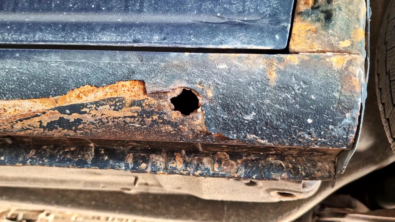 Verrostete Karosserie mit Korrosionsloch zeigt starke Metallschäden und Verfall.