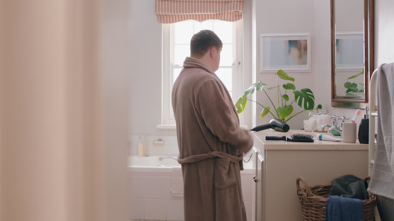 funny teenage boy with down syndrome singing in bathroom using toothbrush having fun enjoying morning routine wearing bathrobe
