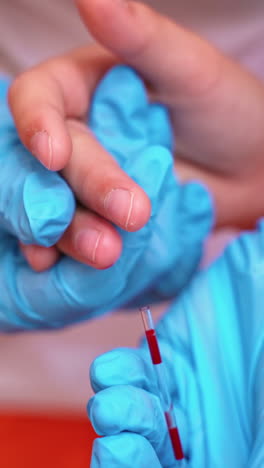 nurse in blue gloves collecting blood. close-up hands of a medical assistant taking blood sample from kid's finger. vertical video