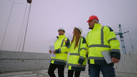 un grupo de ingenieros civiles están caminando en el sitio de construcción arquitecto femenino y capataz masculino