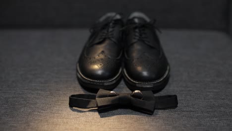 Detalles-De-La-Boda-Del-Novio.-La-Pajarita-Negra,-Los-Zapatos-Y-Los-Anillos-De-Boda-Del-Novio-Yacen-En-El-Sofá.