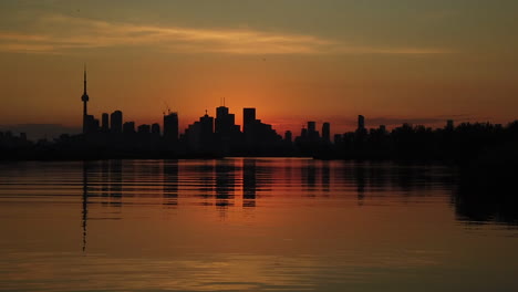 Toma-De-La-Hora-Mágica-En-Cámara-Lenta-Del-Horizonte-De-Toronto-Silueteado-Contra-Un-Cielo-Naranja