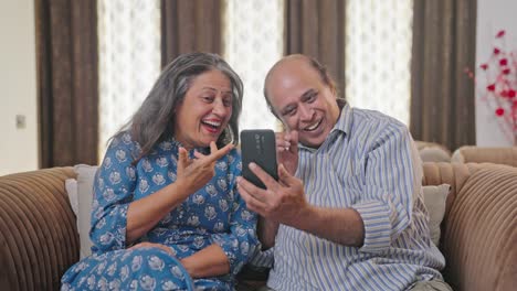 Happy-Indian-couple-talking-to-someone-on-a-video-call