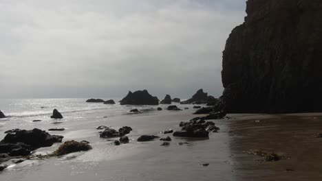aerial view among rock formations at el matador beach, waves crashing on beach shore, cloudy weather