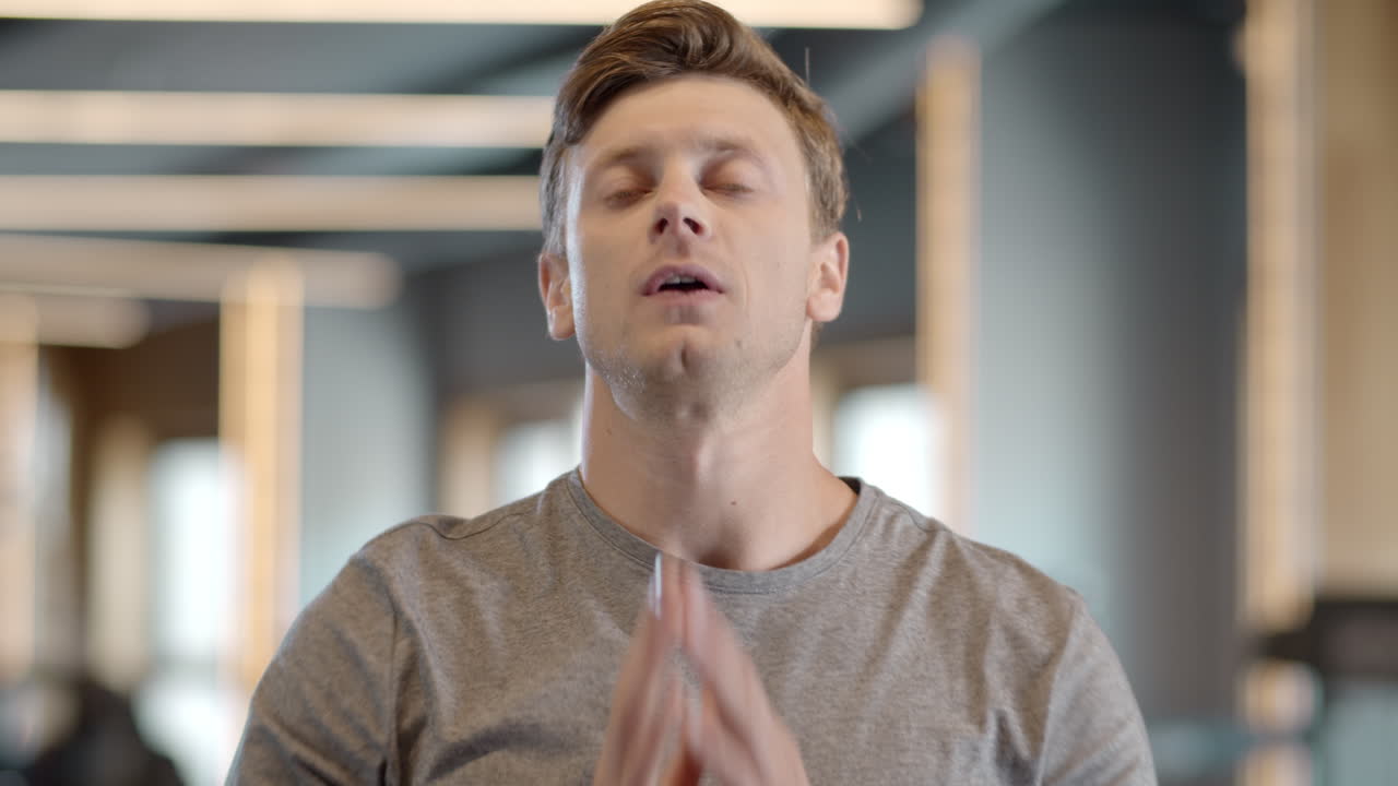 Tired fitness man wiping the sweat at gym. Sportsman standing in fitness center