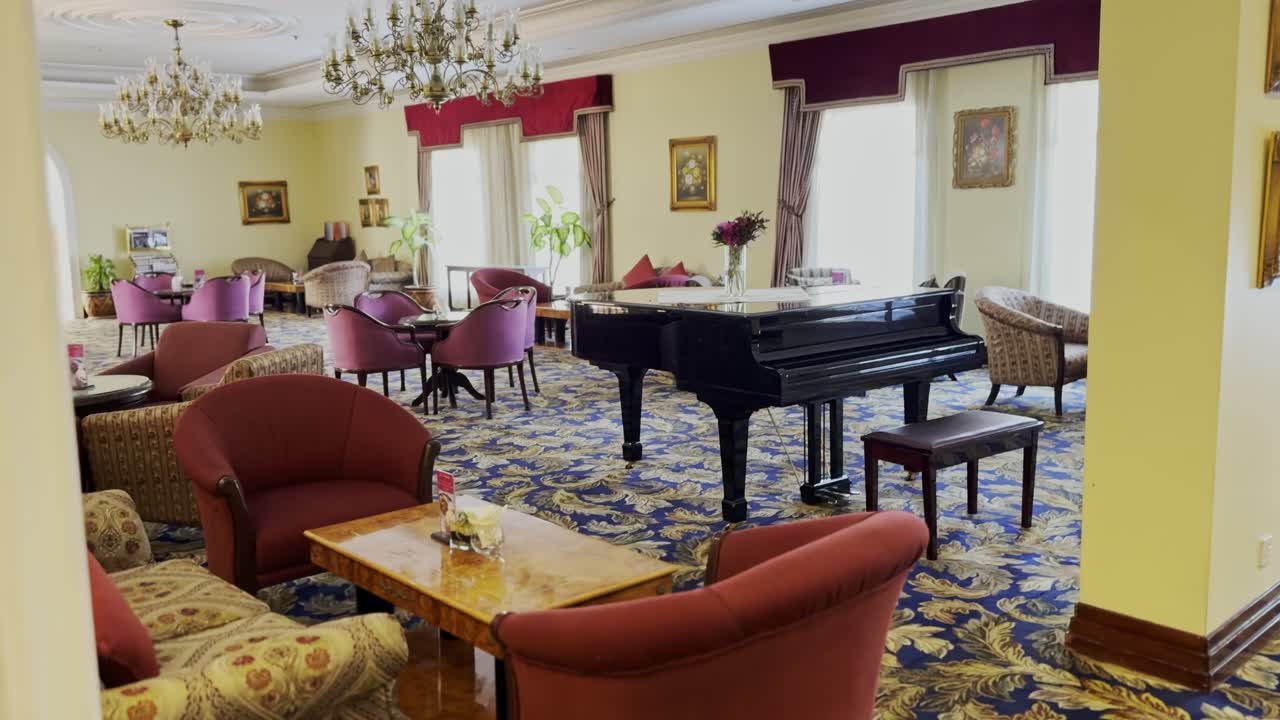 4K footage of a luxurious lounge with chandeliers, velvet chairs, and a grand piano. Ideal for hospitality, lifestyle, and upscale promotional use.