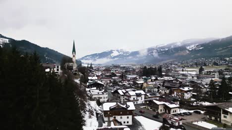 Iconic-Alps-township-with-snowy-landscape-and-church-tower,-aerial-drone-view