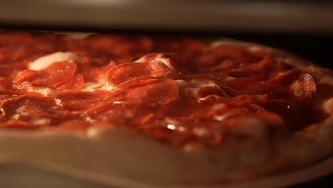 pepperoni baking in the oven with the cheese and oils sizzling in the heat - close up sliding view