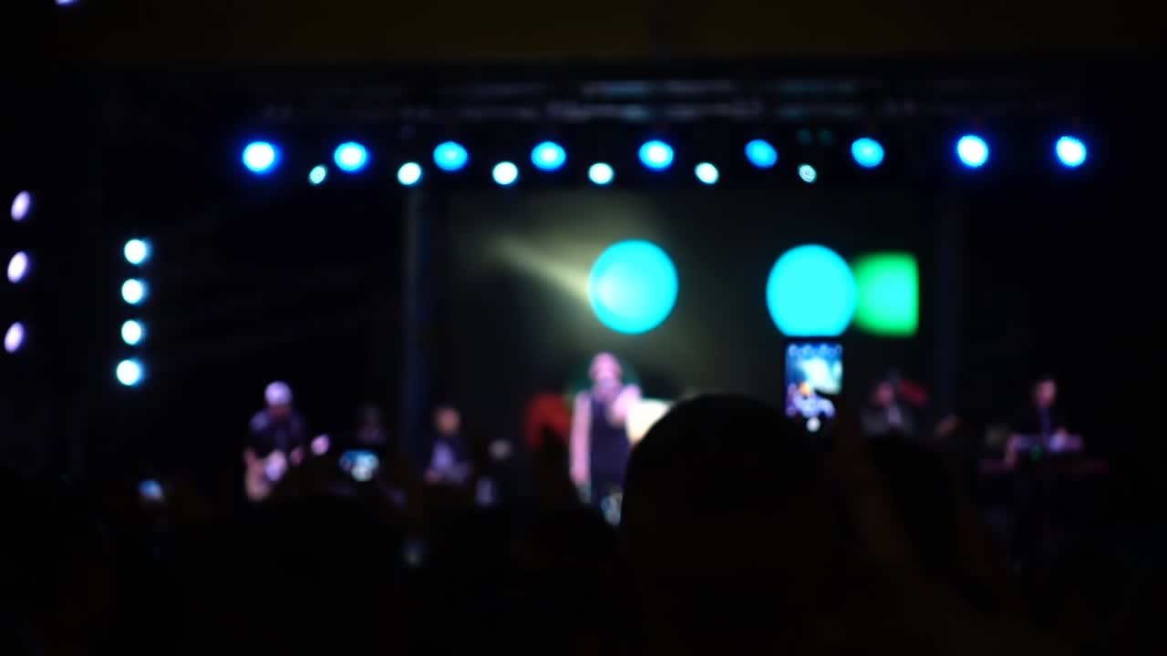 Concert on the stage. Crowd of people and musicians on the scene. Out of focus