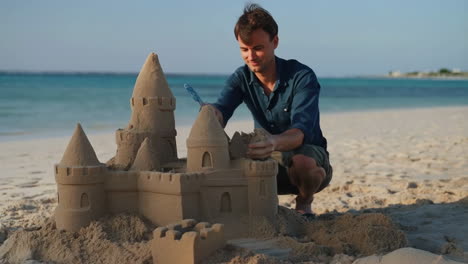 man building a sandcastle on a beach