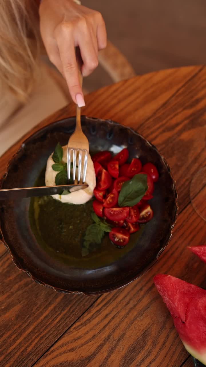 una mujer comiendo ensalada de caprese.
