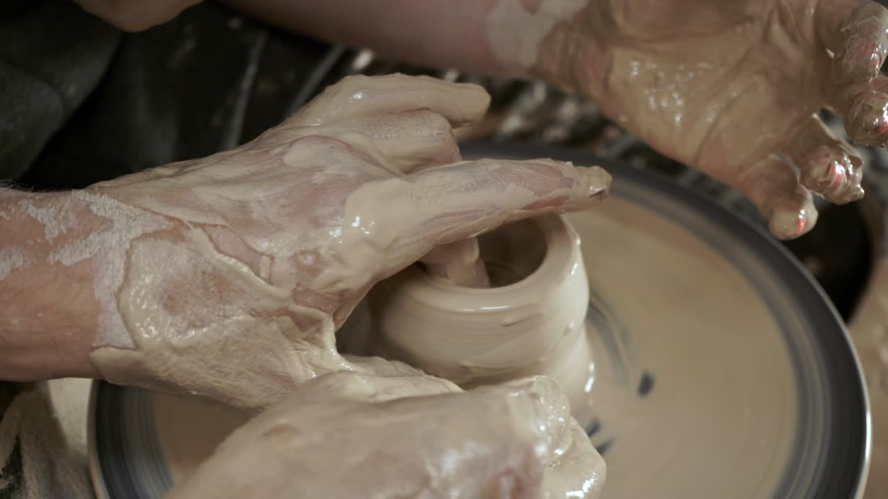 un alfarero enseña a una mujer a hacer platos de arcilla. un hombre toma las manos de una mujer