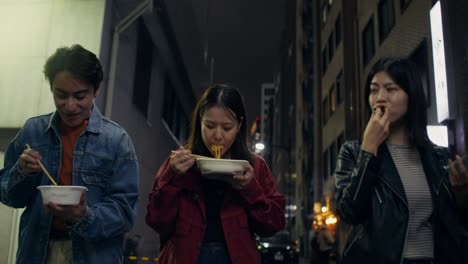friends eating dinner in japanese city street at night