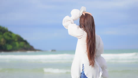 Close-up-of-a-pretty-young-woman-walking-along-the-beach-as-the-surf-comes-in