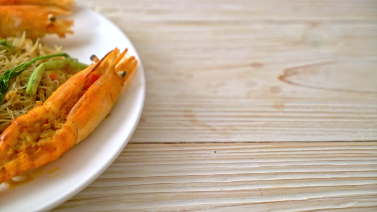 fideos de arroz salteados y mimosa de agua con gambas de río