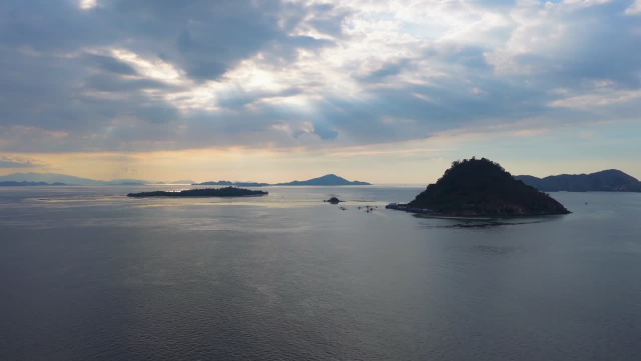 Wide aerial of multiple islands and calm waters under a cloudy sky with soft evening light