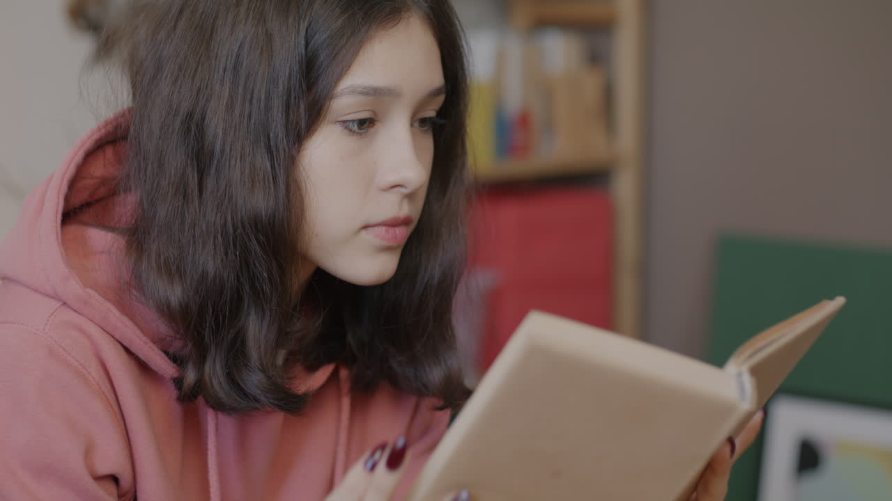 Teenage girl reading a book at home