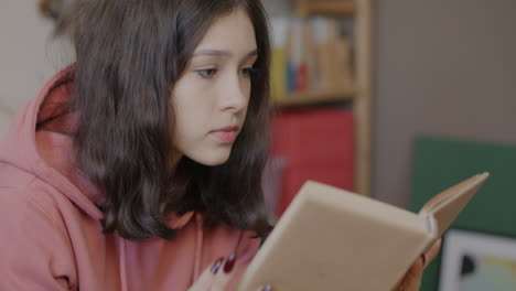 Teenage girl reading a book at home