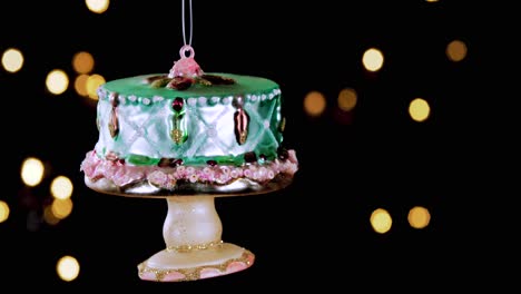 single-birthday-cake-Christmas-ornament-with-out-of-focus-lights-flickering-in-the-background,-close-up