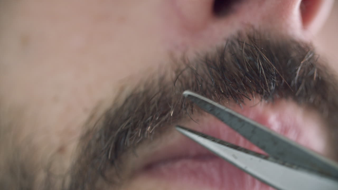 Närbild av en kaukasisk man som trimmar sin mustasch.