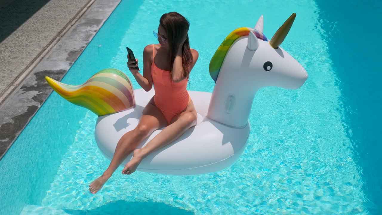 Woman Relaxing in a Swimming Pool on a Unicorn Float